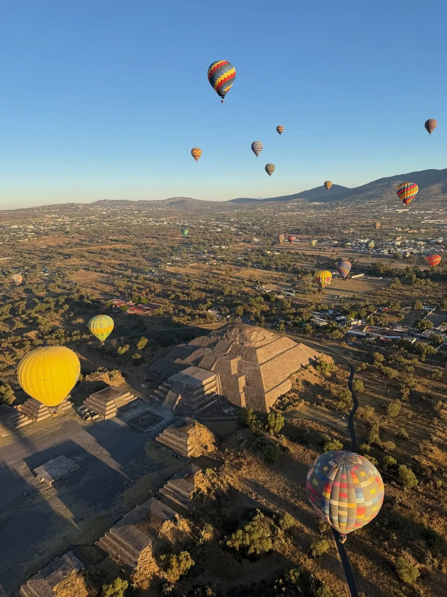 Two hot air balloons drifting beside the Pyramid of the Moon at Teotihuacan