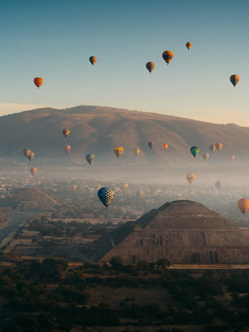 Hot air balloons above the Pyramid of the Sun with the valley stretching to the mountains