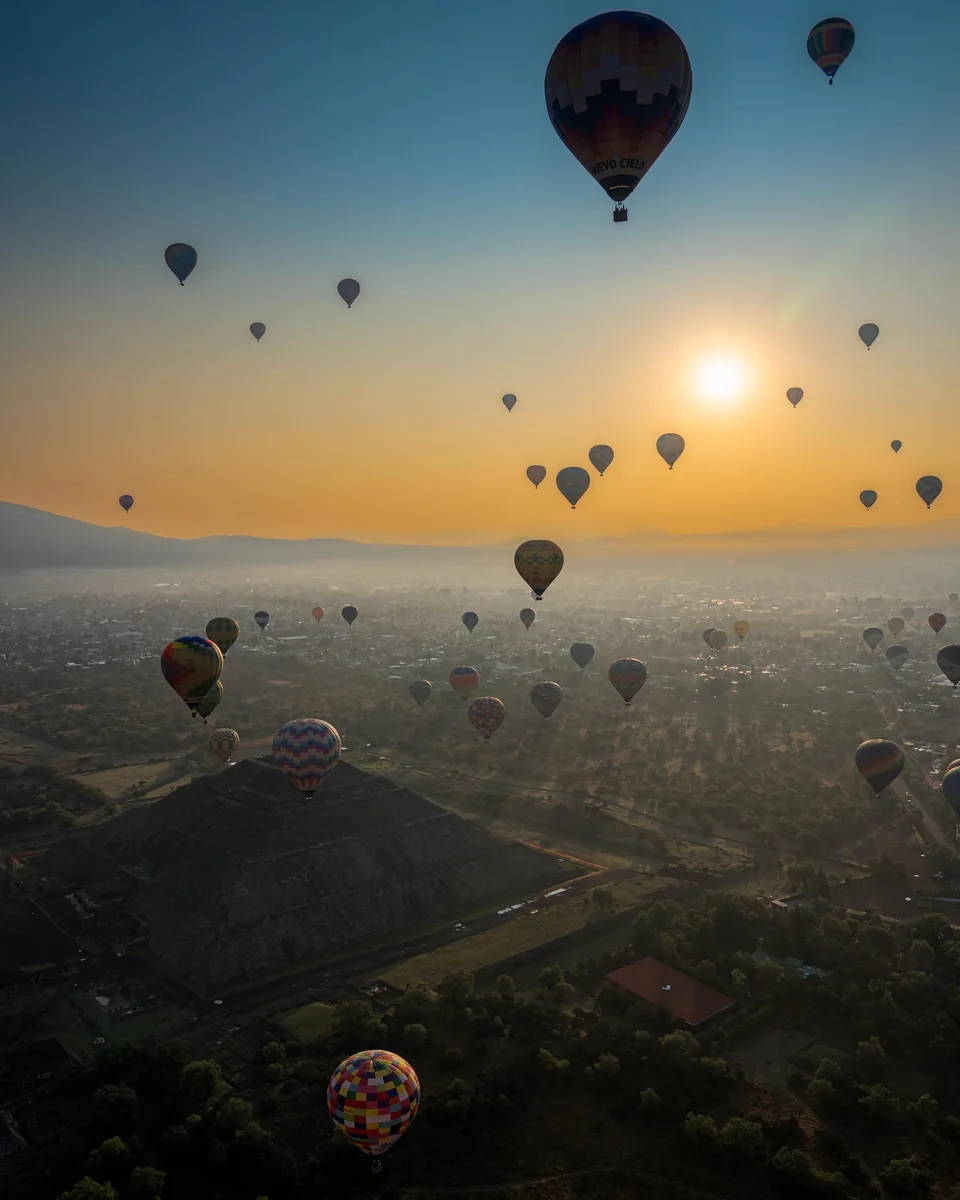 Hot air balloons silhouetted against the rising sun over the Teotihuacan valley