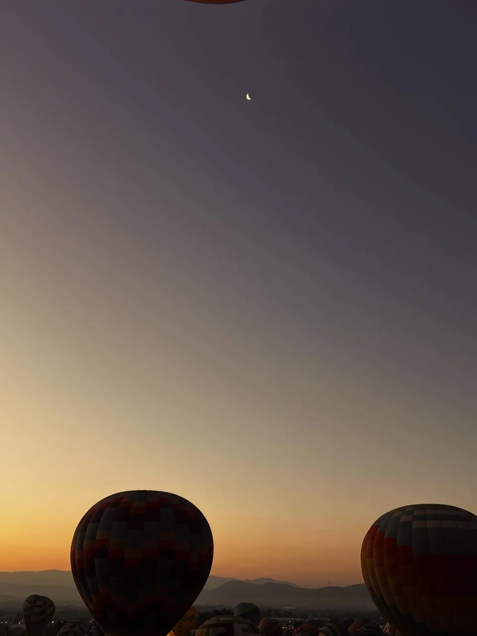 Hot air balloons lifting off through the morning haze at Teotihuacan