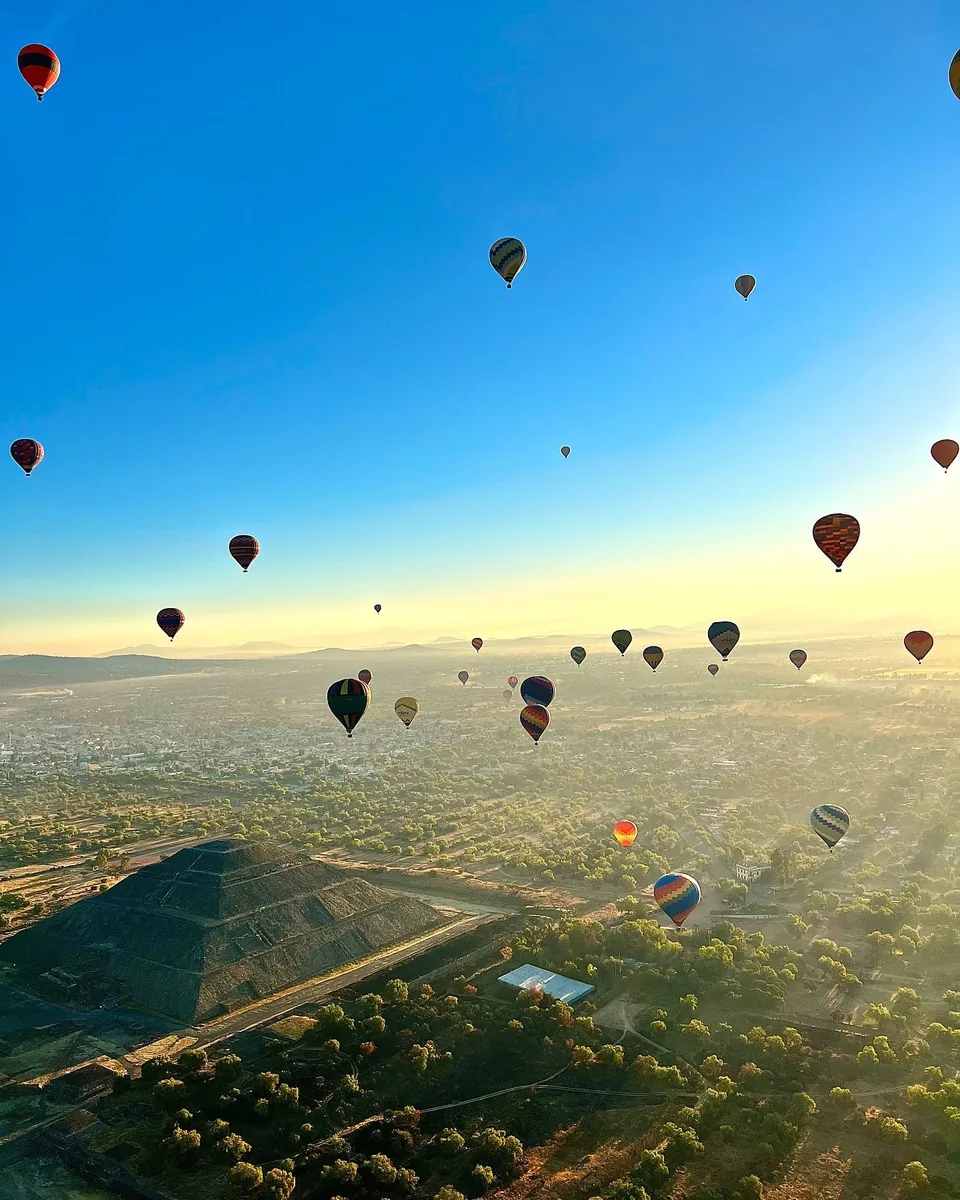 Hot air balloons spread over the Teotihuacan valley under a clear blue sky