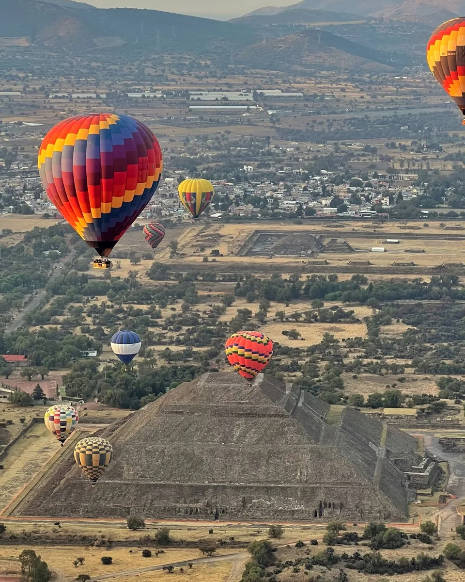 Colourful hot air balloons passing over the Pyramid of the Sun