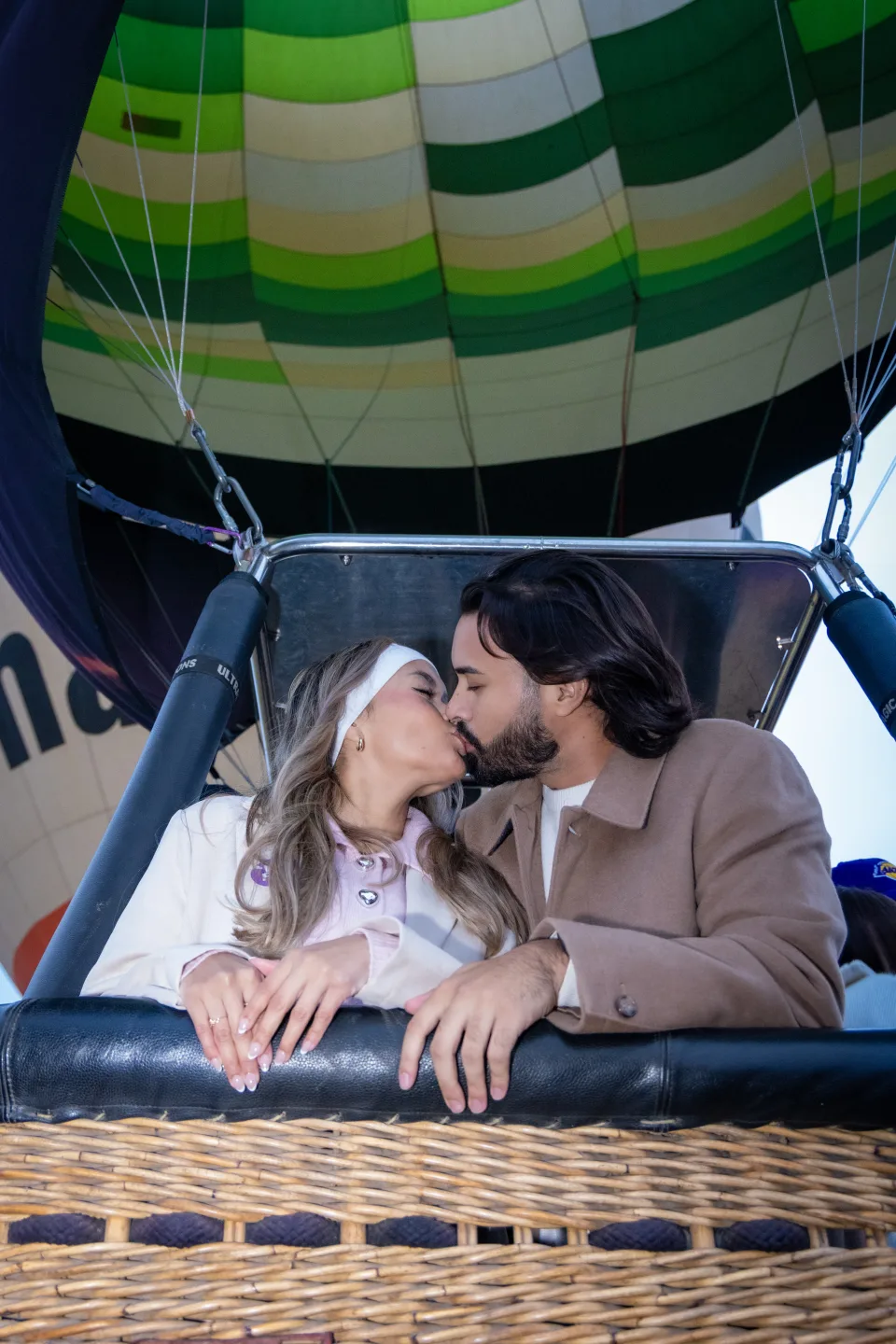 Pareja besándose dentro de la canastilla de un globo aerostático al amanecer en Teotihuacán