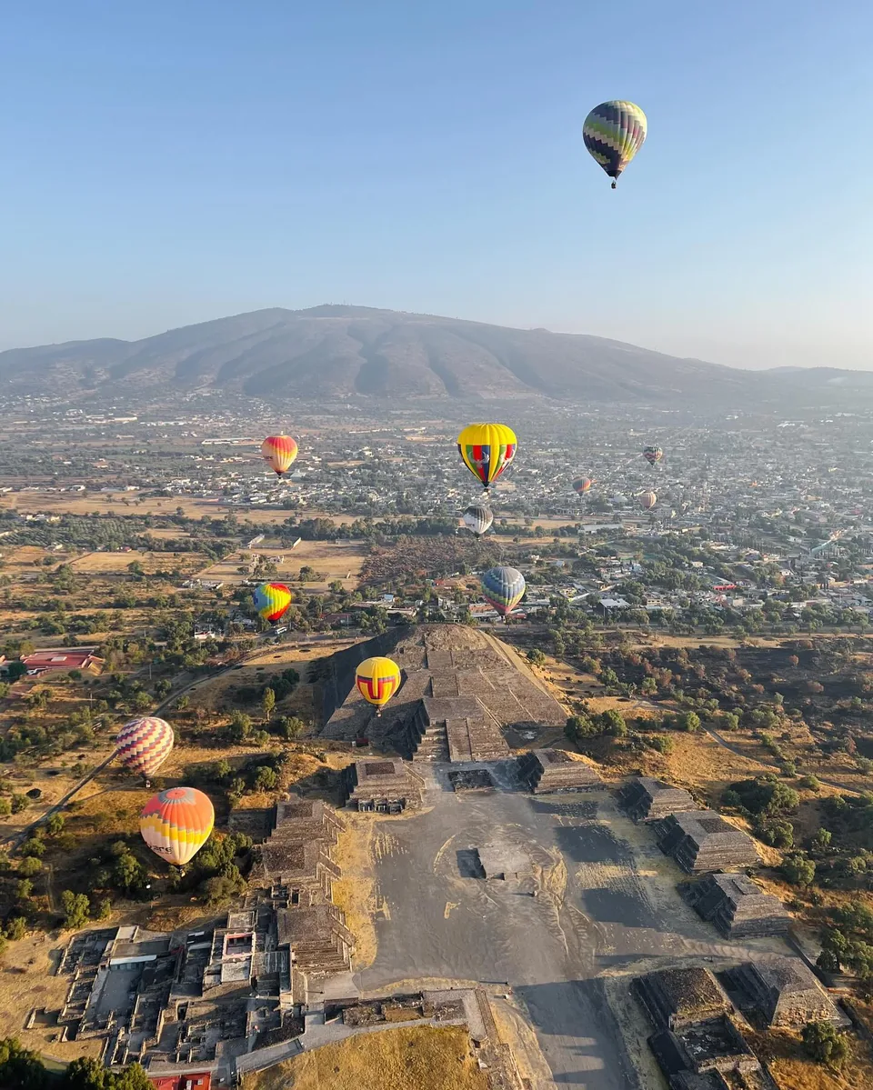 View from a hot air balloon basket flying along the Avenue of the Dead over the Teotihuacan archaeological zone at sunrise