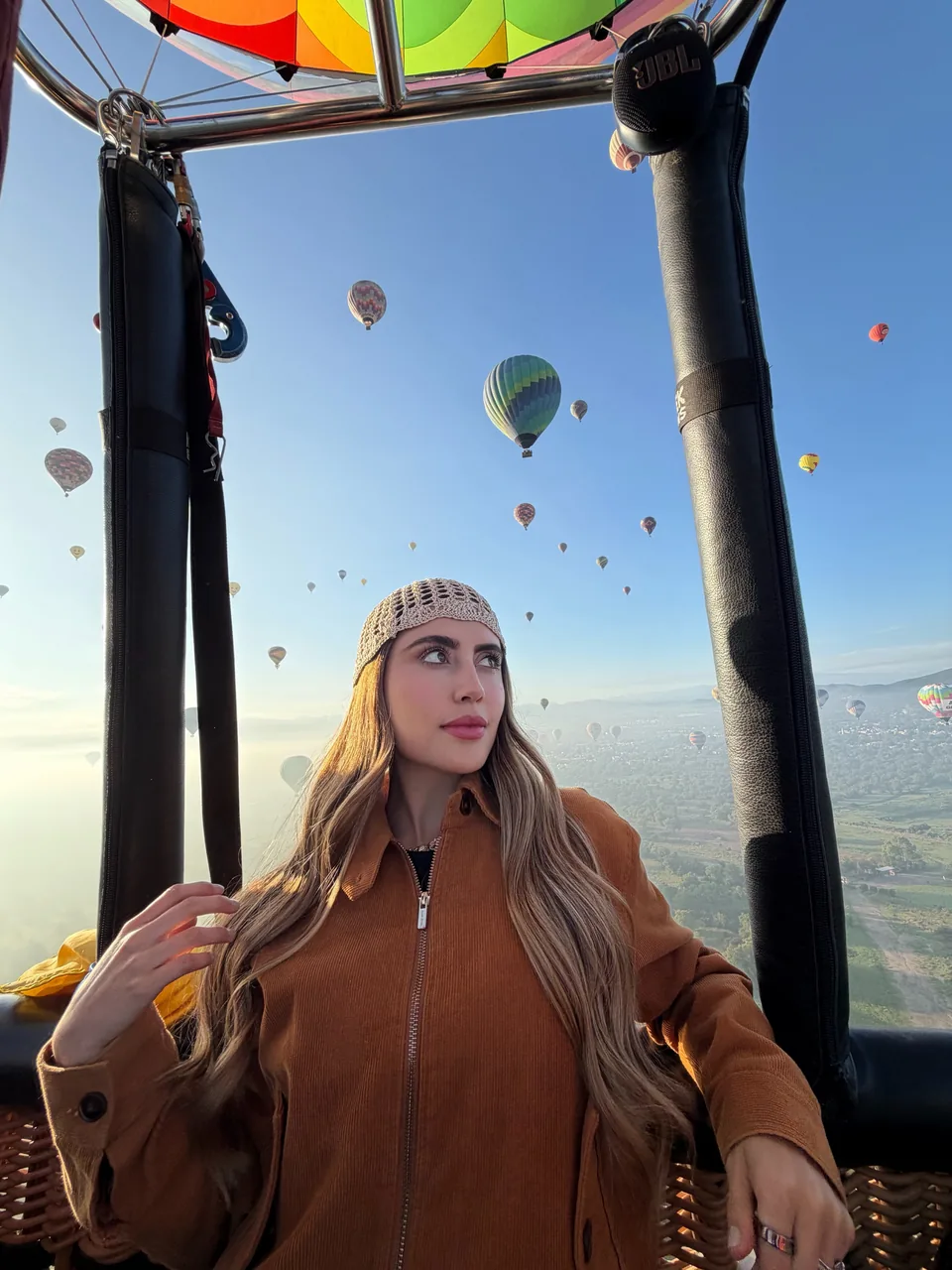 A passenger in flight over Teotihuacan at dawn with balloons on every side