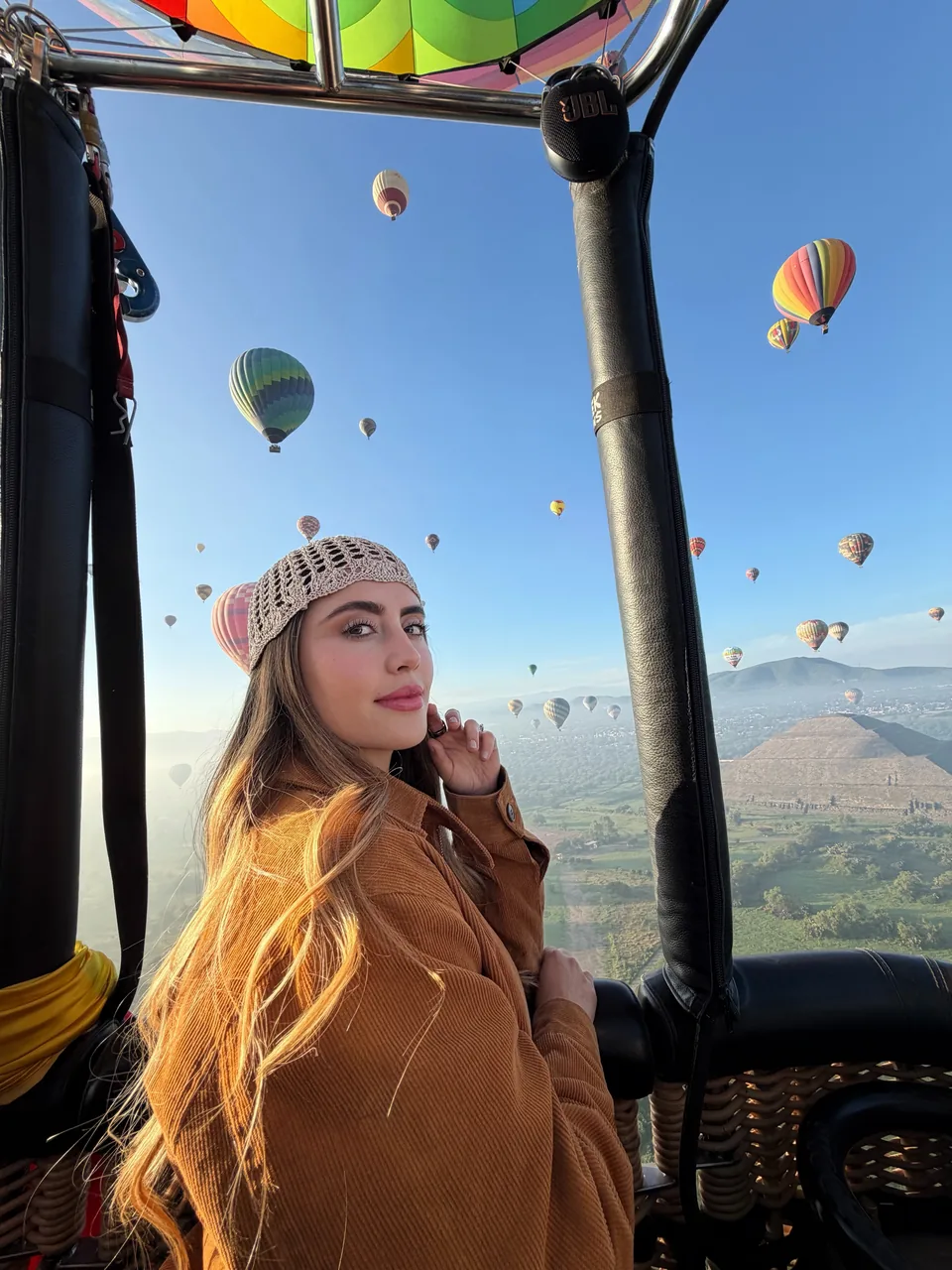 A passenger looks out from the basket toward the Pyramid of the Sun in the morning haze