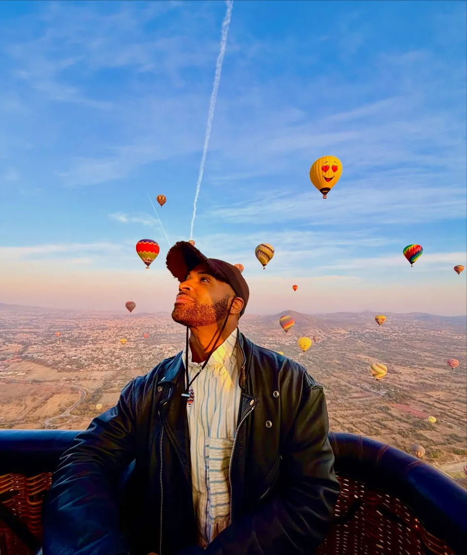 A passenger looks up at the balloons drifting overhead from inside the basket
