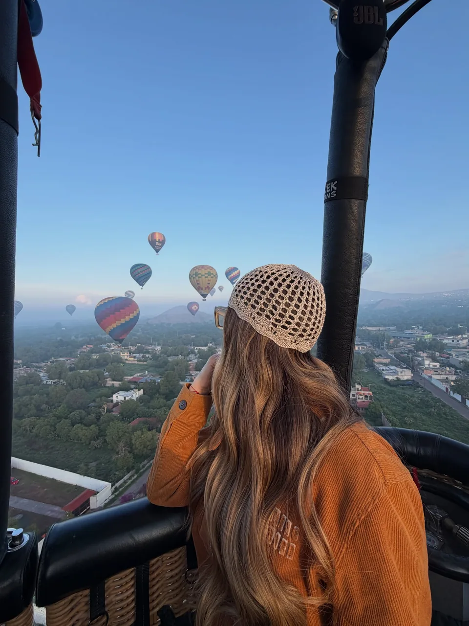 A passenger leans on the basket rail watching the Teotihuacan valley pass below