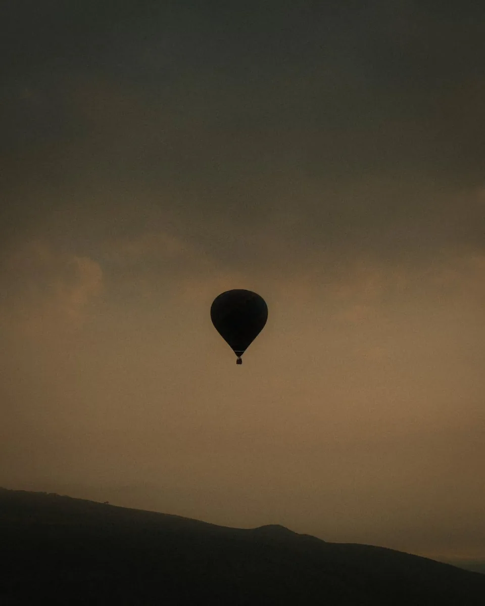A single hot air balloon floating above a layer of morning fog in the Teotihuacan valley