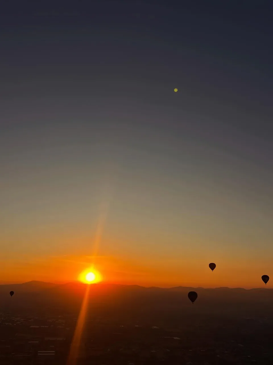 The sun clearing the horizon over Teotihuacan, seen from inside a hot air balloon basket