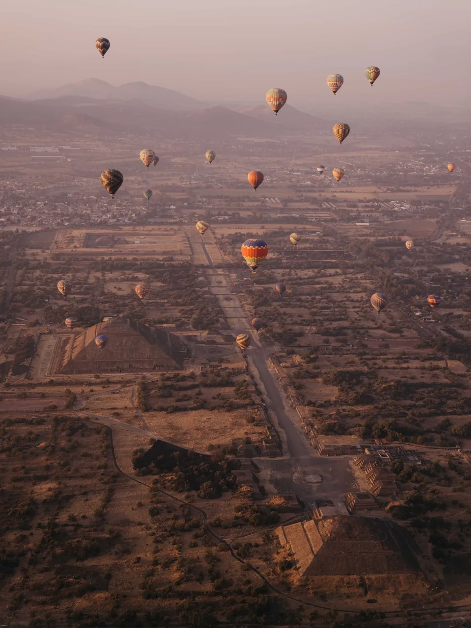 The Teotihuacan archaeological zone with balloons scattered over it at dawn