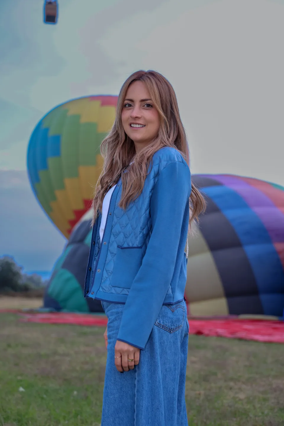 Mujer de perfil con globos aerostáticos en el campo de despegue detrás al amanecer